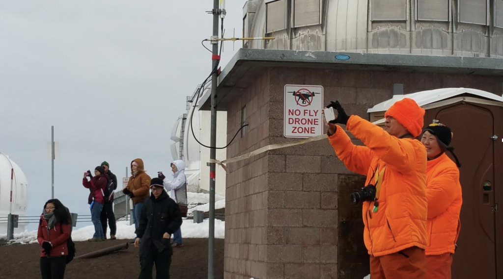 Tourists bundled up against the cold outside the observatories take pictures on top of Maunakea. 