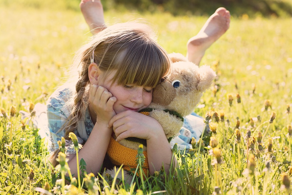 girl with stuffed toy in field