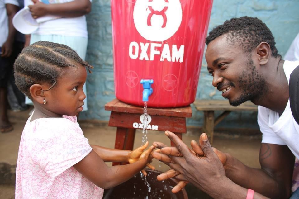 Oxfam aid worker supplies water to child