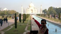 Young boy poses in front of the Taj Mahal.