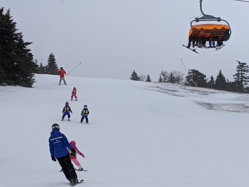 Ski school lesson at Okemo with Sunburst 6 Bubble lift overhead