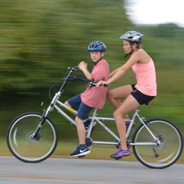 Two people on adaptive cycle at NEDS school