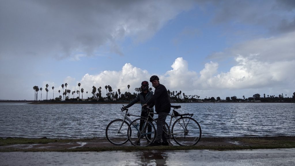 Two bike riders rest on the Mission Bay Bike Trail in the rain