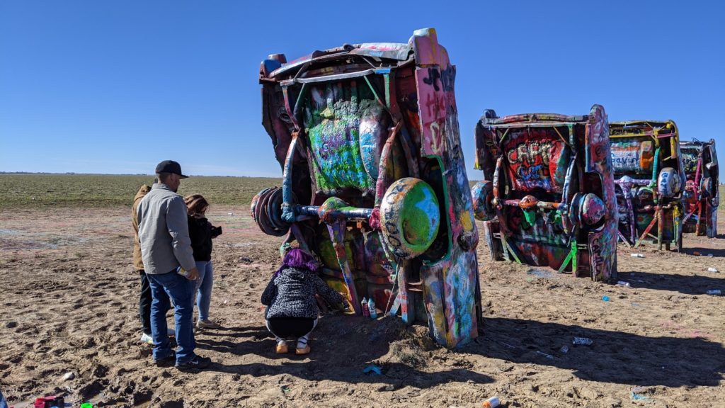 Visitors adding graffiti to Cadillac Ranch artwork in Amarillo, Texas.