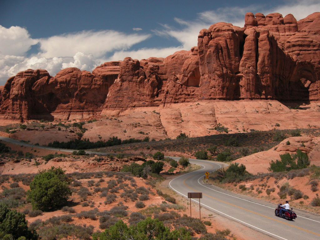 Motorcycle driving past Courthouse formation at Arches National Park, Utah