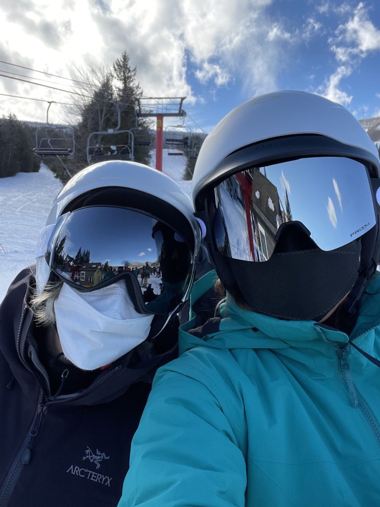 two women skiers post for selfie in goggles and face masks