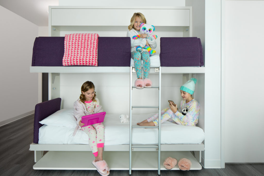 Three girls sit on bunk beds in their room at YotelPAD Park City in Utah.