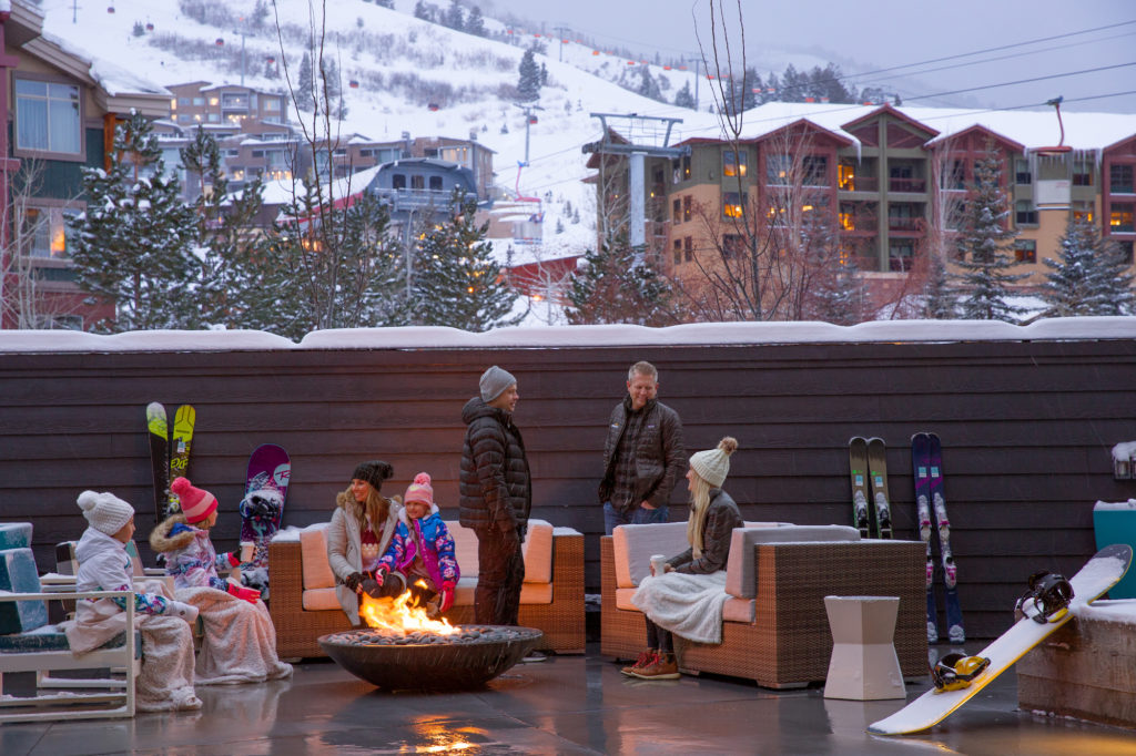 Two families sit in front of a firepit on the patio of YotelPAD Park City in Utah.