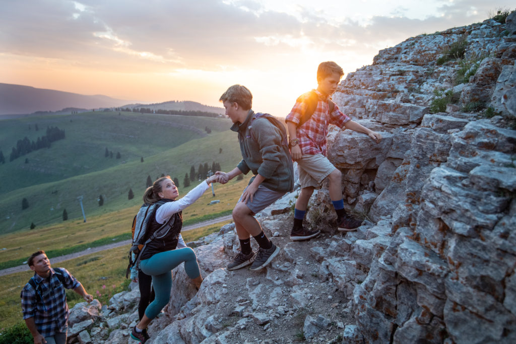 Parents and kids are scrambling over rocks on summer hike in Vail Valley.