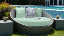 Pale green daybed on lawn in front of pool.