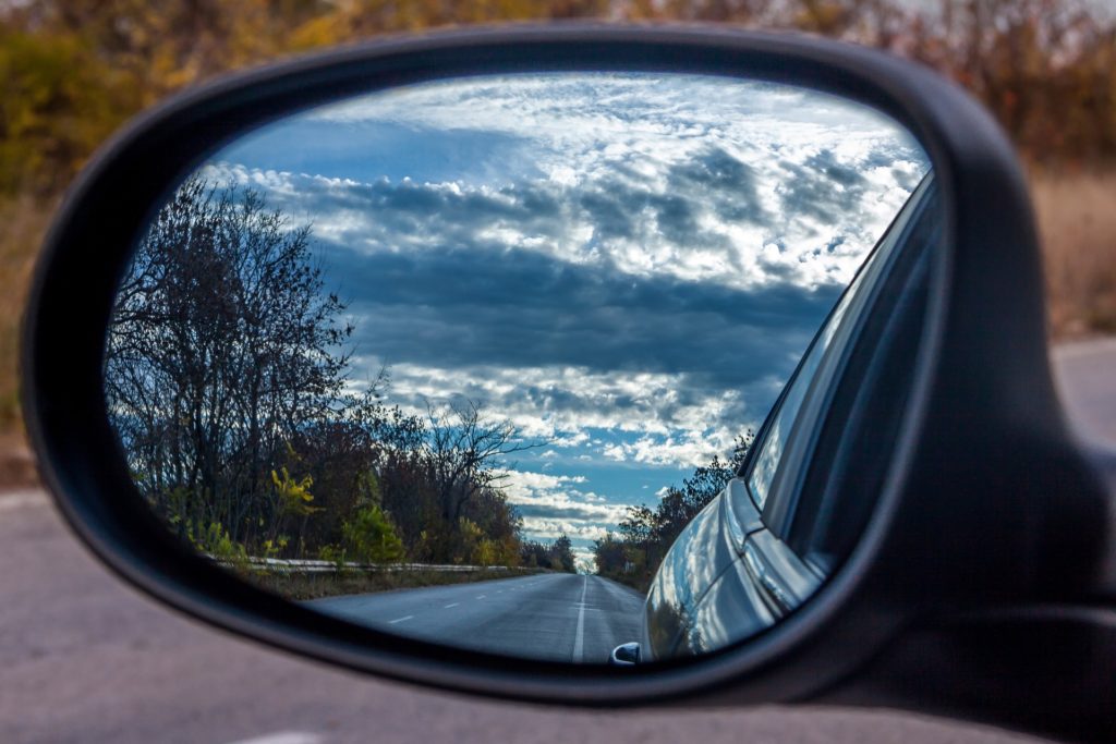 Rearview mirror with a road receding into the distance.