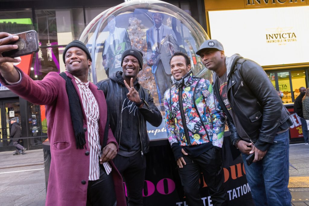 Cast members of "Ain't Too Proud", the Temptations musical, pose in Times Square with their Show Globe. Photo c. Times Square Alliance