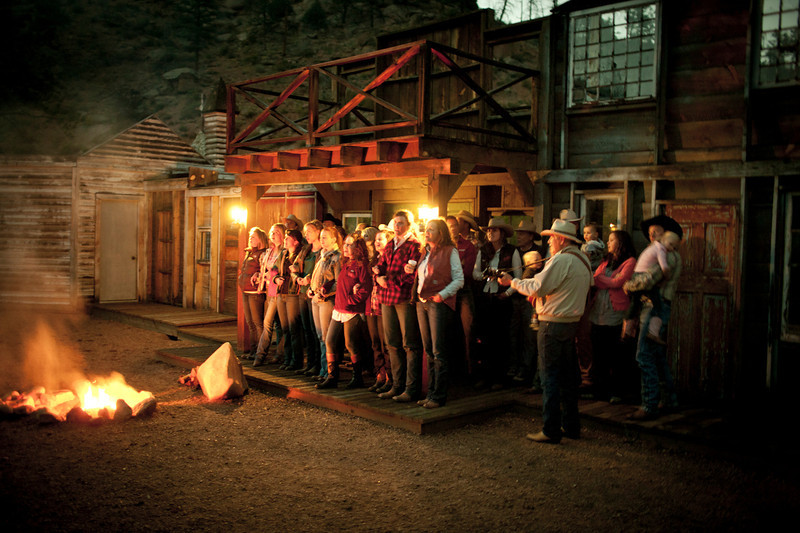 Group of ranch guests singing songs around the campfire at the Lost Valley Ranch in Sedalia, Colorado.