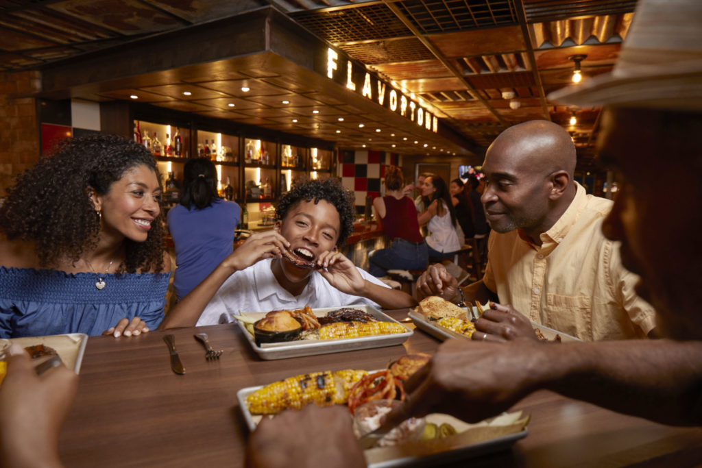 Family and young boy enjoying lunch at Guy's Pig & Anchor barbecue restaurant aboard Carnival ships.