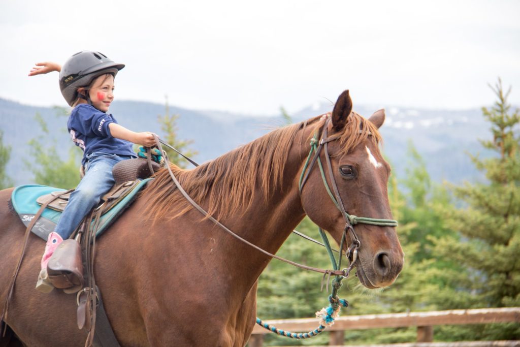Young girl rides a brown horse at Vista Verde Ranch, Clark, Colorado.