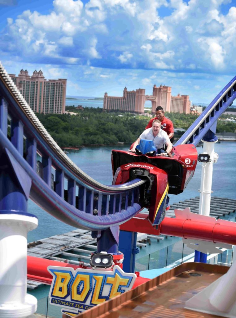 Two men ride Bolt Coaster on deck of Carnival Mardi Gras ship while moored at Atlantis, Bahamas.