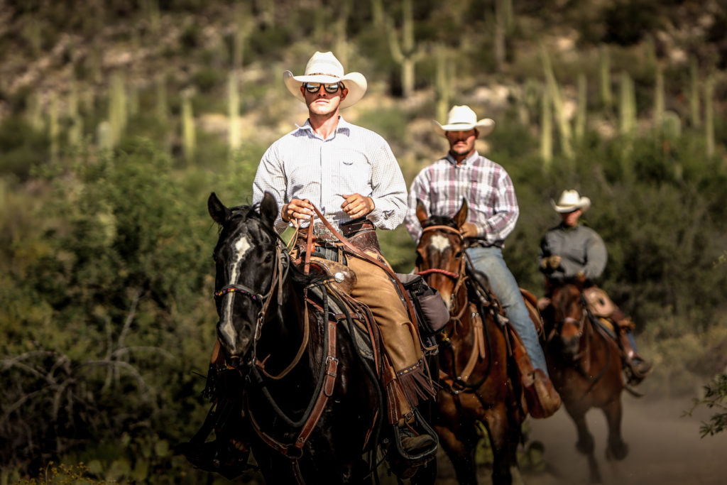 Men on horseback lope along a trail at Tanque Verde Ranch outside Tucson, Arizona