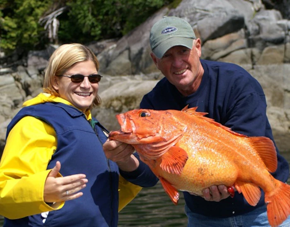 Happy couple holds up a huge pink salmon they caught in Alaska.