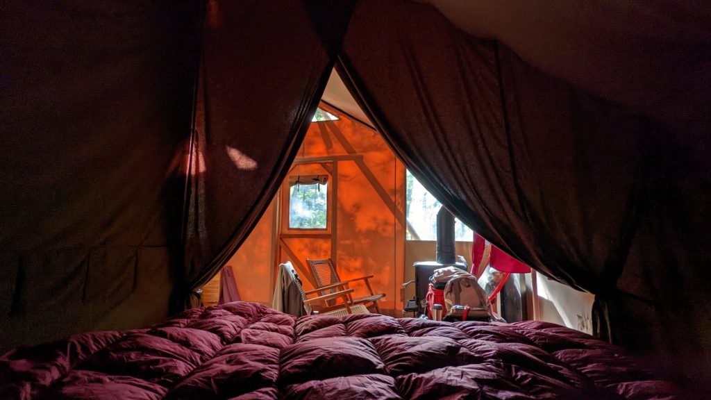 View from our tent's king bed out the front canvas windows of a Huttopia Adirondacks Trappeur family tent.