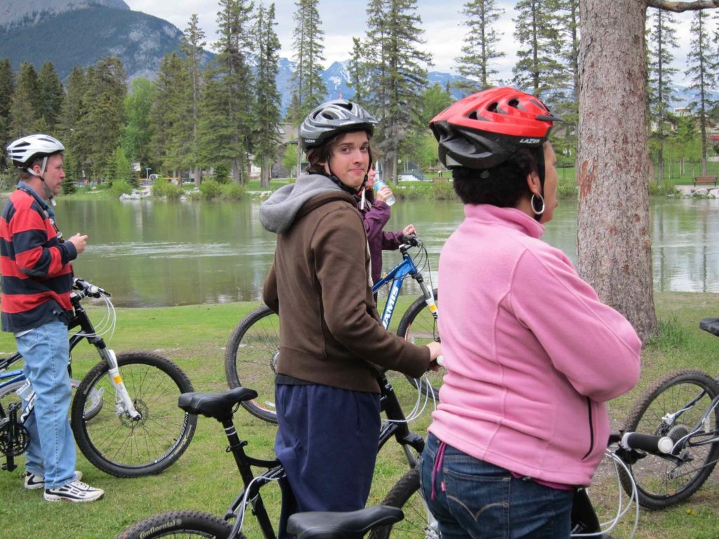Group on mountain bikes next to a lake listens to a guide.