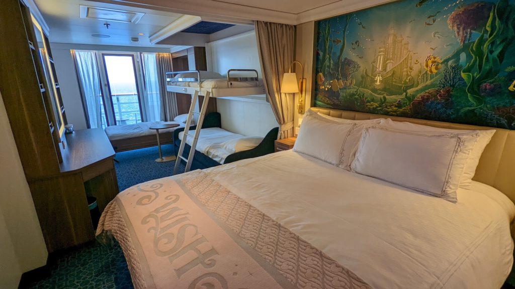 Family stateroom aboard the Disney Wish has its sofa, upper berth and wall-bed down to reveal room for five passengers.