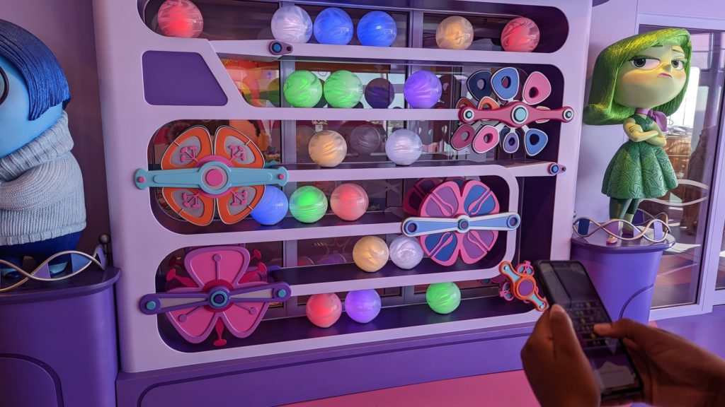 Girl using cellphone app to play a game in the Joyful Sweet Candy shop aboard the Disney Wish cruise ship.