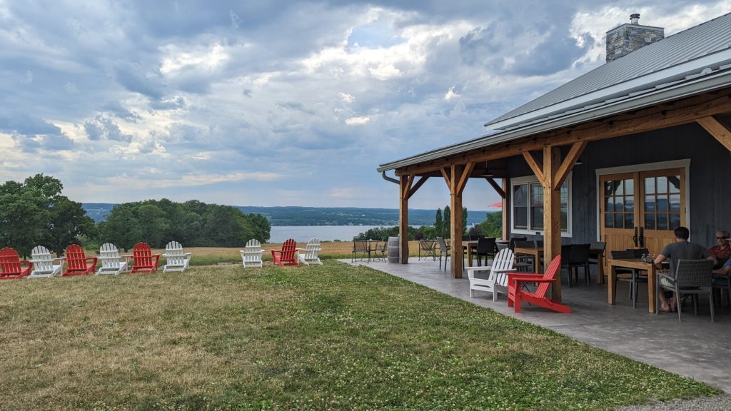 Red and white Adirondack chairs overlook Lake Cayuga in the Finger Lakes, New York