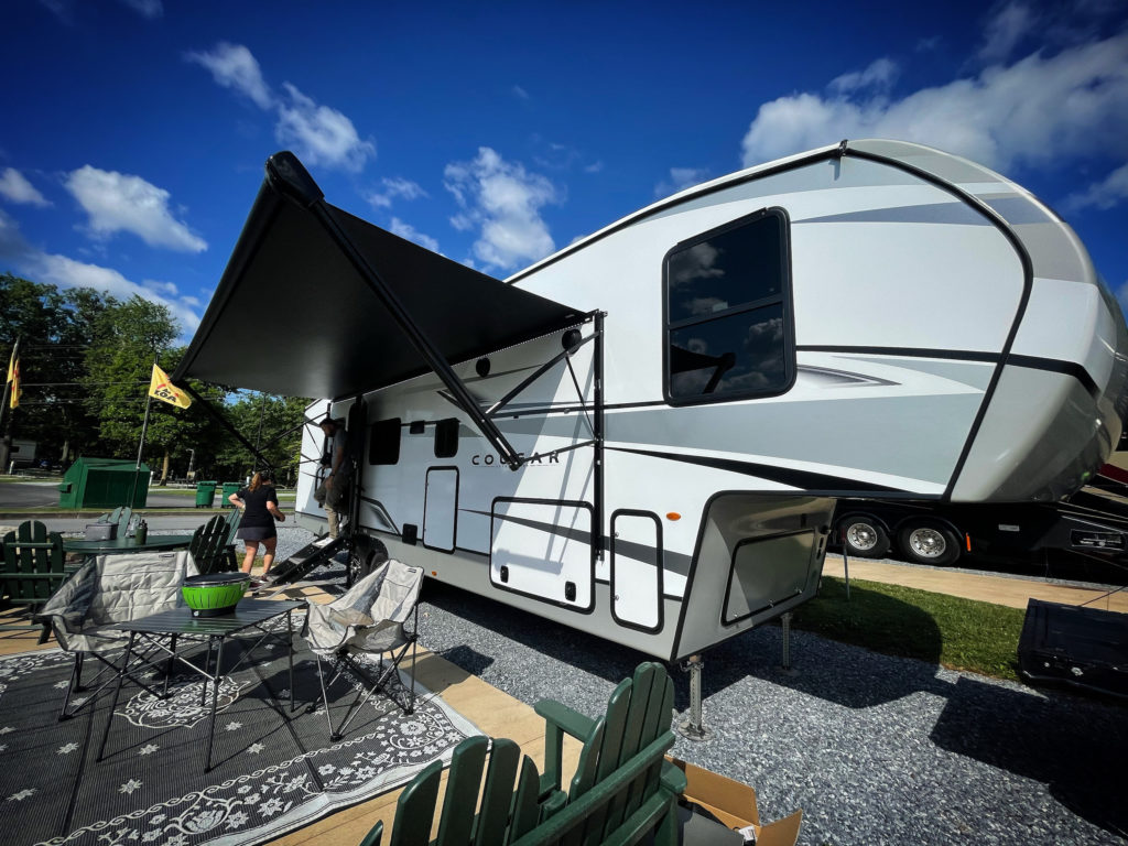 A portable patio setup outside a Cougar model RV home parked at KOA Harpers Ferry, West Virginia.
