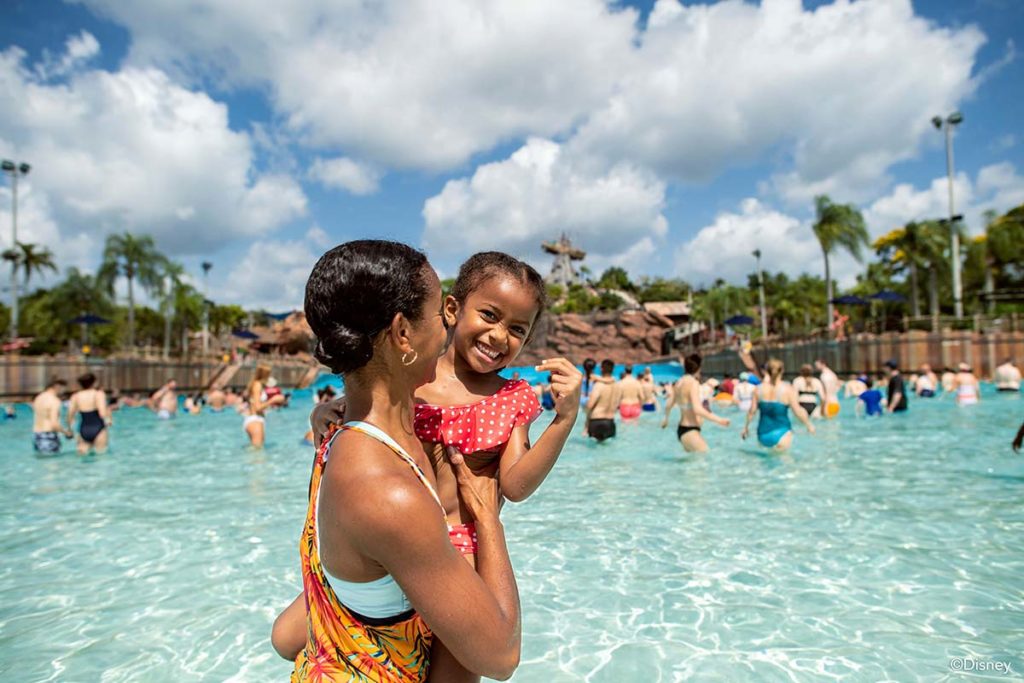 Mother holds up smiling daughter in water park pool at Walt Disney World Resort, Orlando. Photo c. Disney