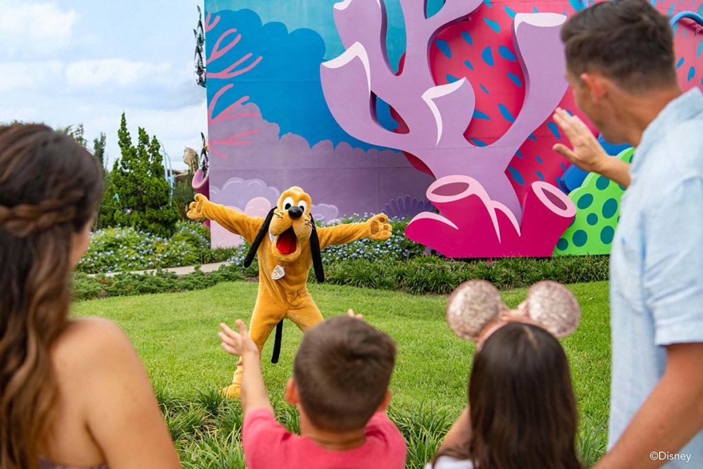 Family reaches out to greet Pluto, the Disney character, at Walt Disney World Resort in Orlando. Photo c. Disney