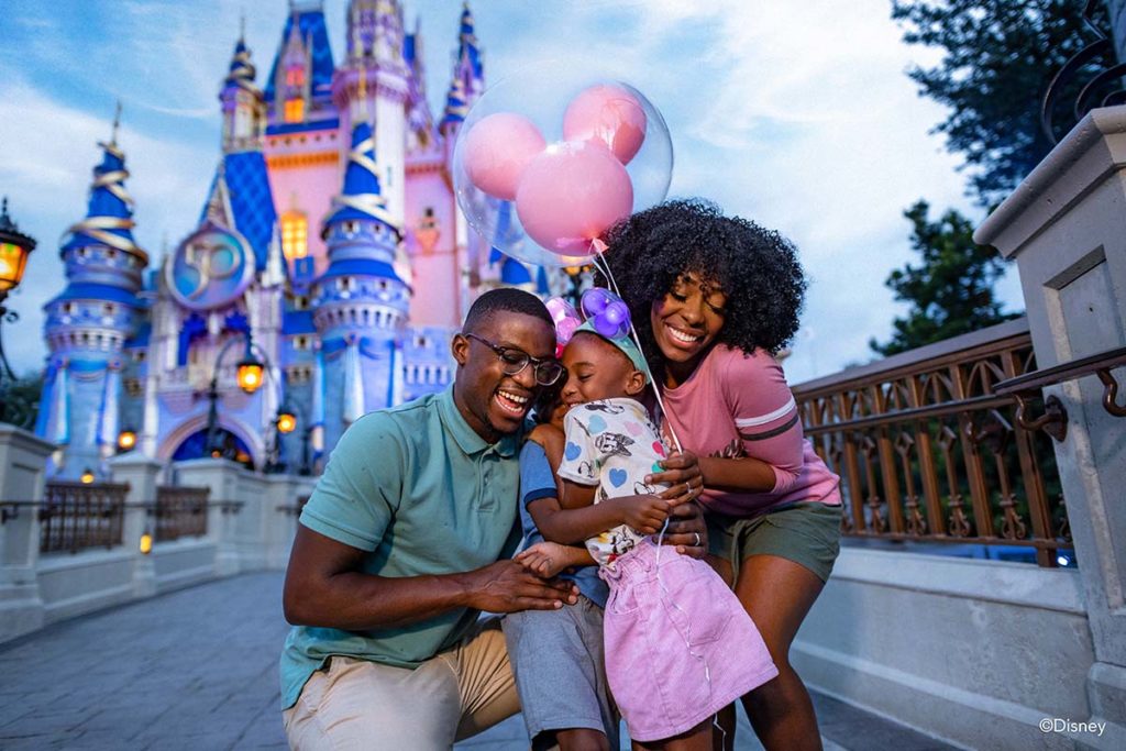 Couple with two children celebrate the Walt Disney World 50th Anniversary at the EARidescent Cinderella Castle, Walt Disney World Resort, Orlando. Photo c. Disney