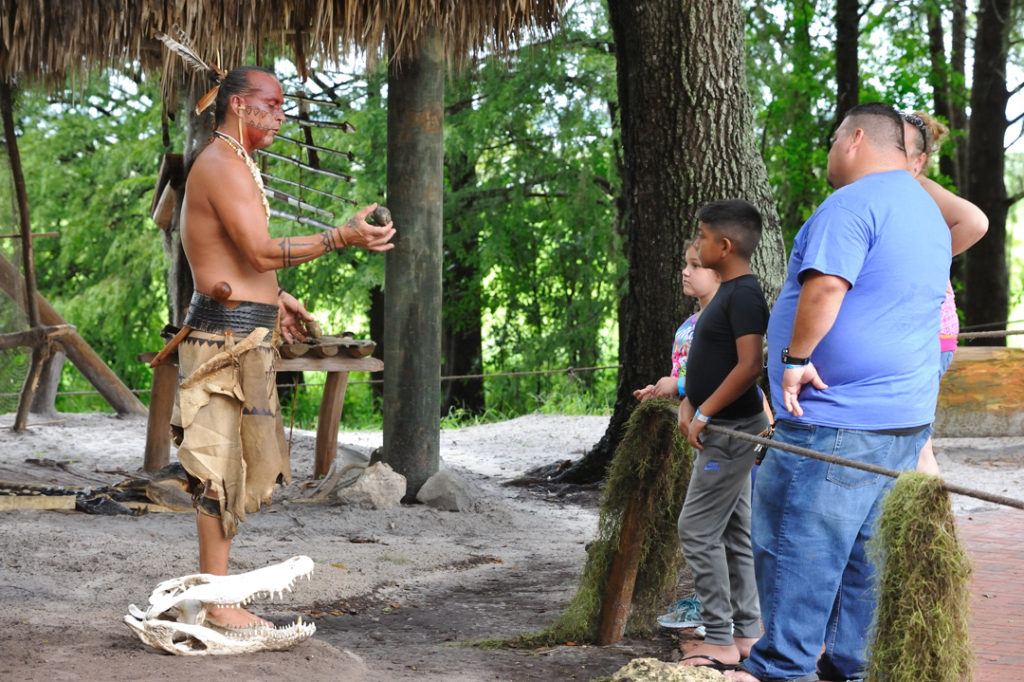Guide in traditional Native costume shows off finds from the Everglades at Boggy Creek Airboat Rides Native American Village attraction.