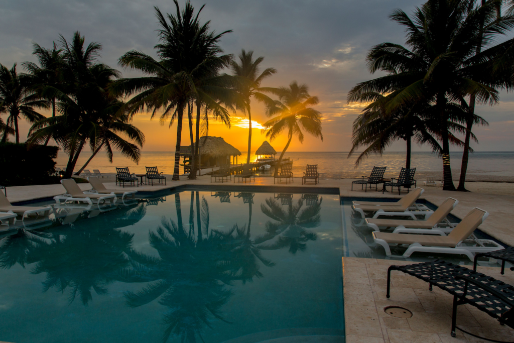 Pool at Victoria House with palm trees reflected in Belize at sunset.