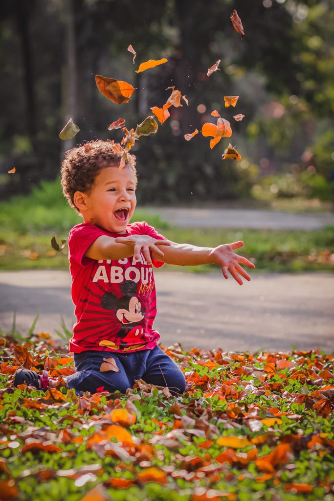 Young boy throws leaves in the air.