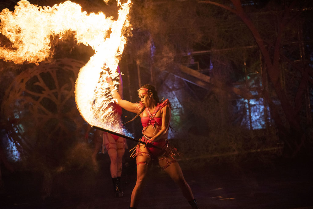 Woman in red costume with flame thrower and dark stage background, from Universal Studios Florida.