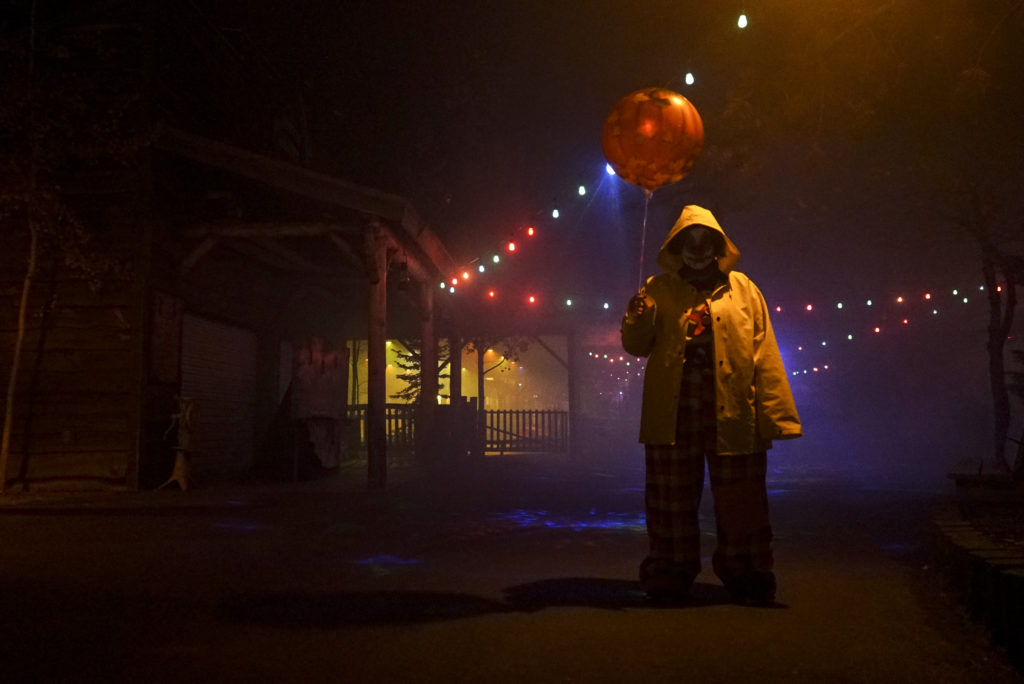 Scary figure in clown outfit and yellow poncho walks with balloon at Scarywood, at Silverwood theme park in Idaho. Photo c. Visit Idaho.