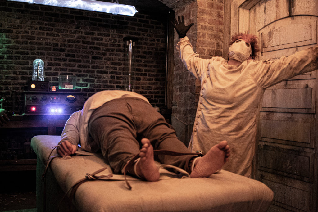 A spooky surgeon operates on a fat man on a table at the 13th Gate haunted house in Baton Rouge, Louisiana. Photo c. Haunted America.