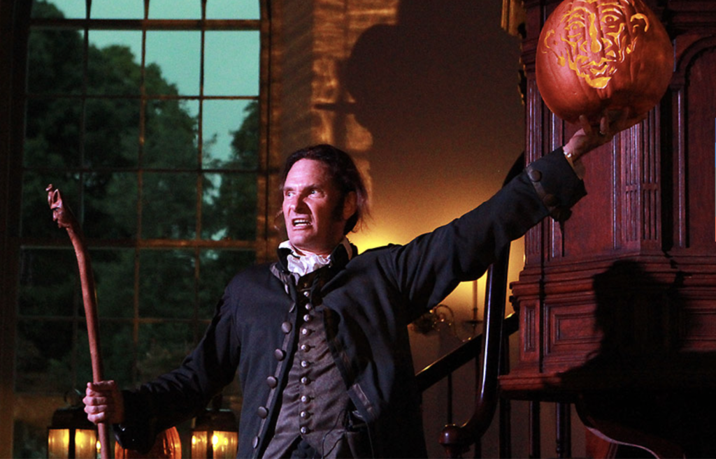 Actor in costume holds up a staff and carved pumpkin at Washington Irving's Legends show at Sunnyside, Tarrytown, New York.