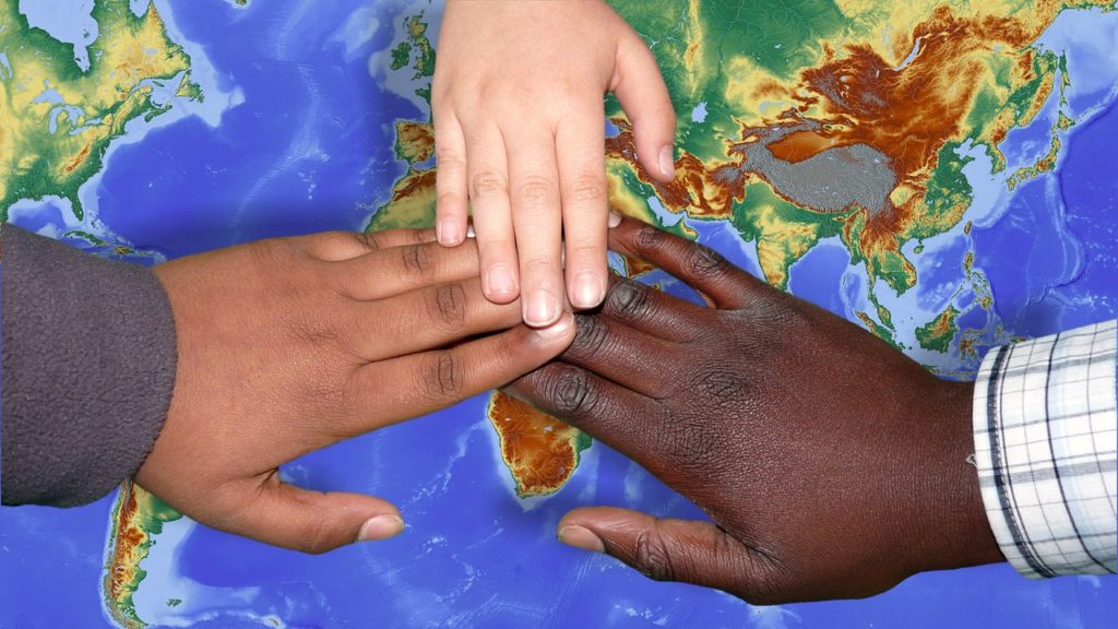 three hands touch on world map, phono by Ralph's Photos for pixabay.