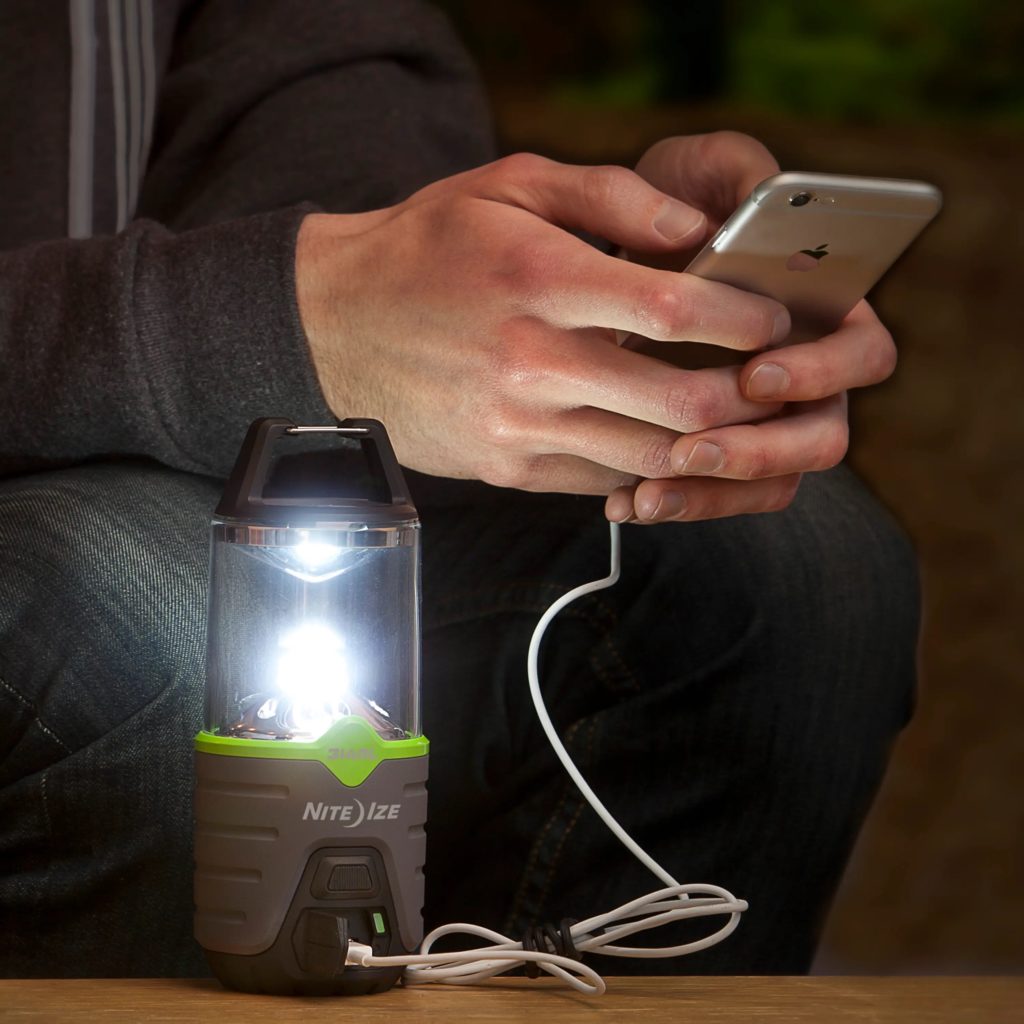 Man charges cellphone with Niteize portable lantern.