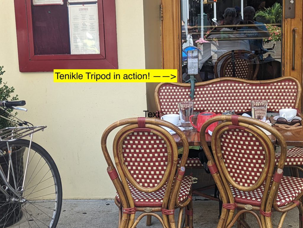 Red and white checked chairs at outdoor cafe with sign in front.