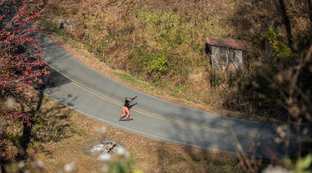 A skateboarder on a winding road, aerial view.
