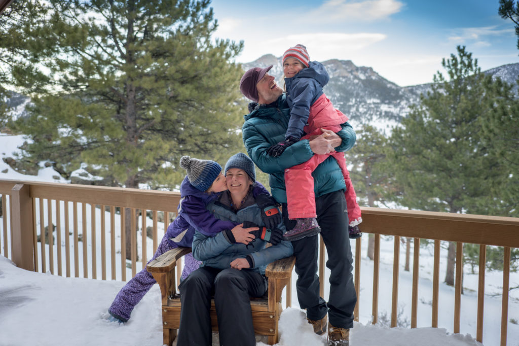 Family on snow-covered porch of cabin at YMCA of the Rockies Estes Park.