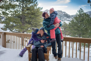 Family on snow-covered porch of cabin at YMCA of the Rockies Estes Park.