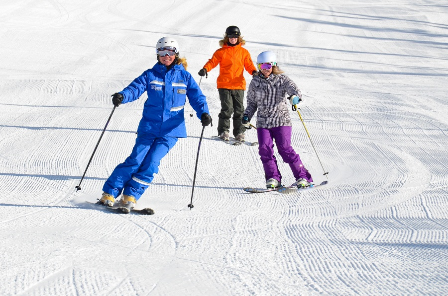 Two women skiing with a female Vail Resorts instructor at Vail Mountain in Colorado.