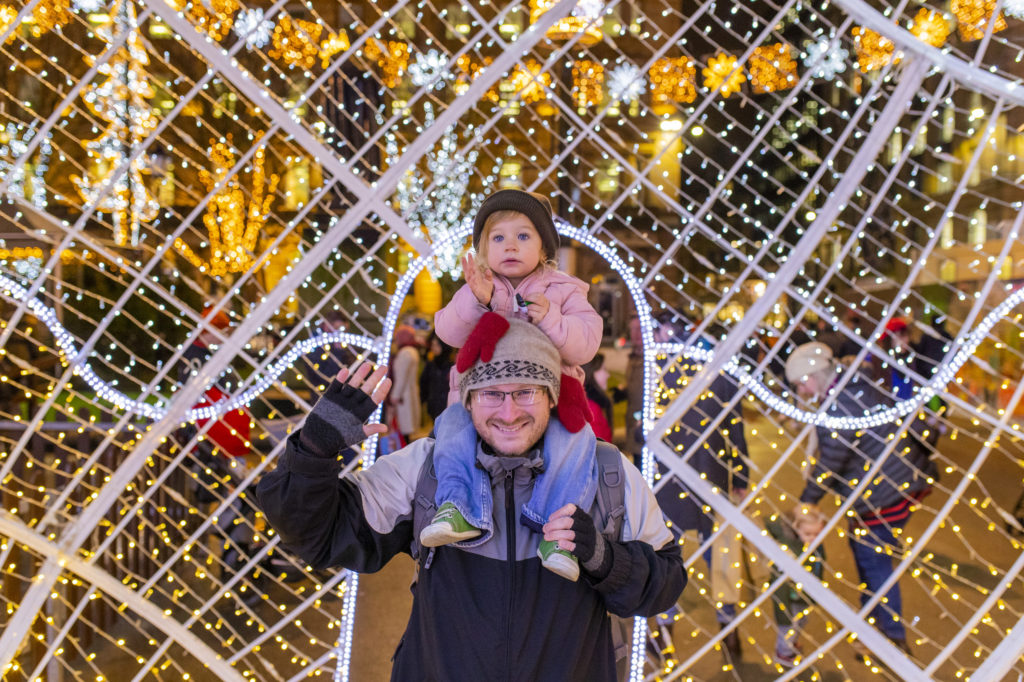 Man and child pose with background holiday lights at the George Square Christmas Market, Glasgow. Photo c. VisitBritain/Scott Salt