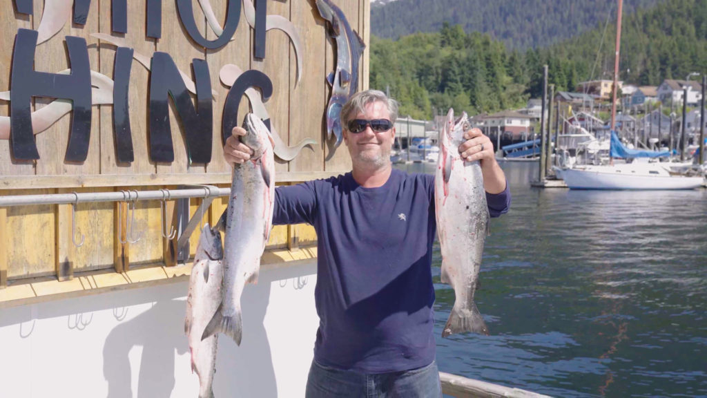 Man holding two fish he has caught in Alaska on a Princess Cruise Lines excursion.