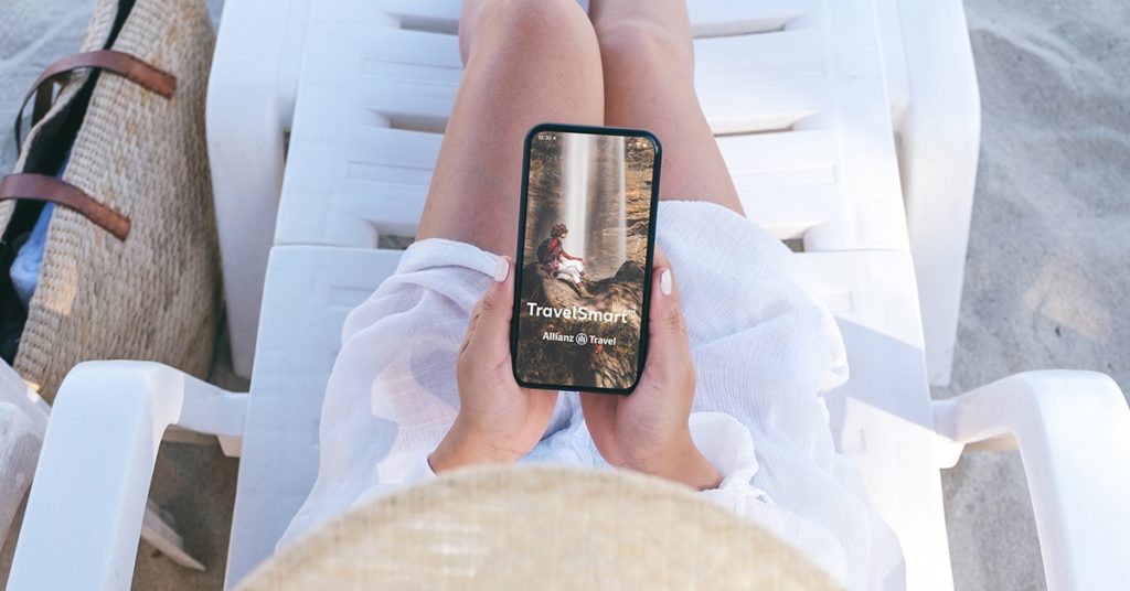 Woman on a beach chair looks at smartphone.