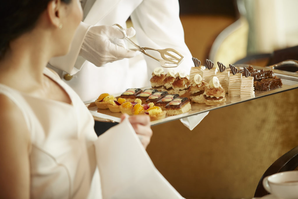 Woman being served miniature pastries on a Cunard ship.