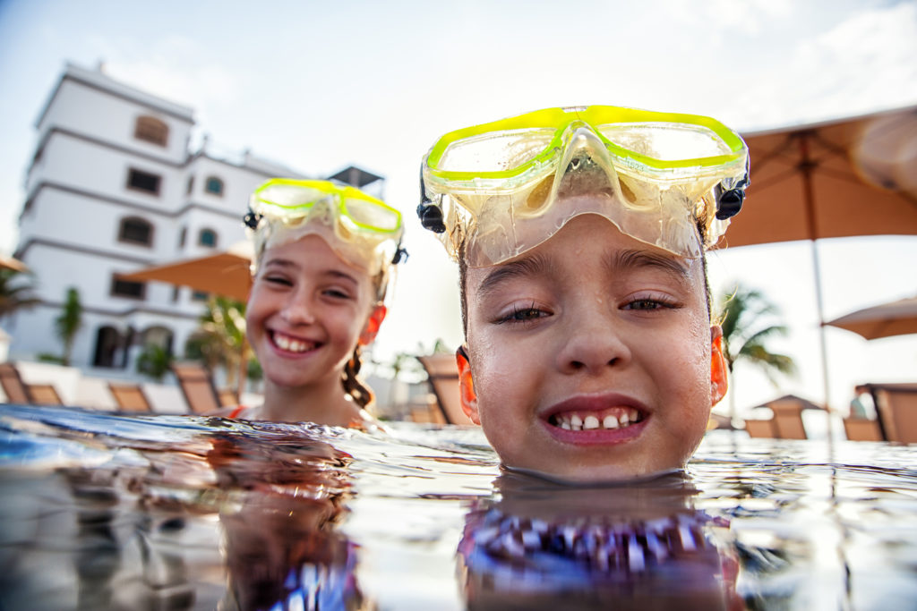 Two kids with snorkel masks smile in the pool at Grand Residences Riviera Cancun Resort.